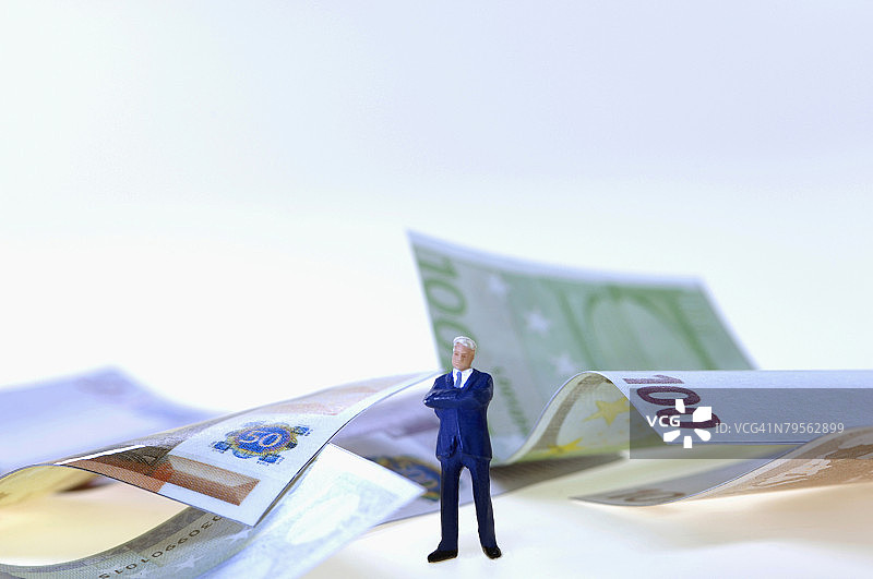 商务人士人偶，背景是钱，特写图片素材