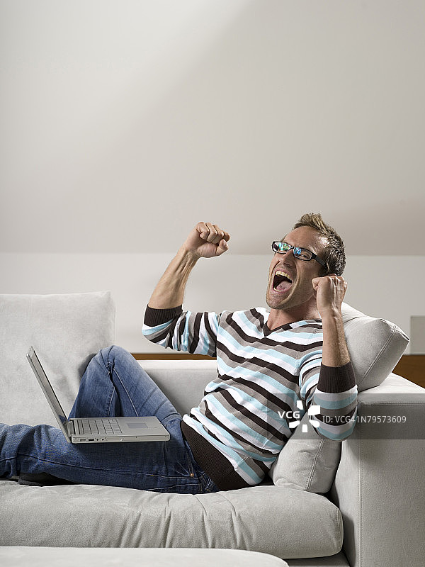 男人坐在沙发上使用笔记本电脑图片素材