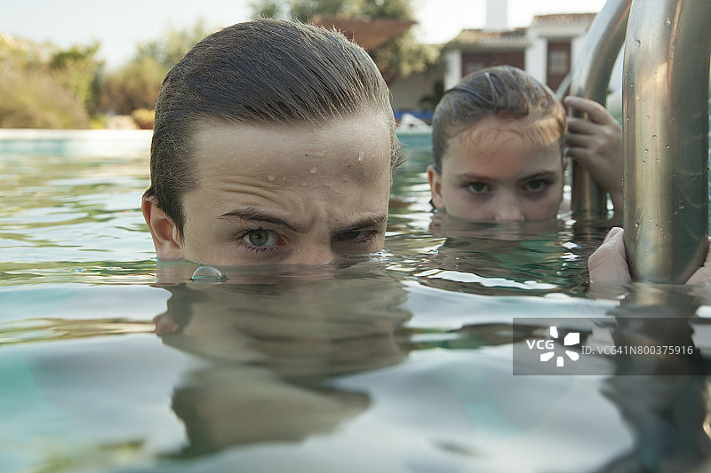 泳池里的孩子们，看起来令人担忧和害怕。青少年在游泳池水面窥视，惊悚极地风格图片素材