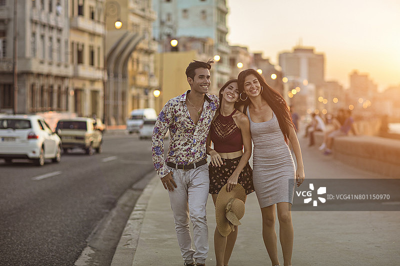 日落时分在人行道上散步的快乐朋友们图片素材