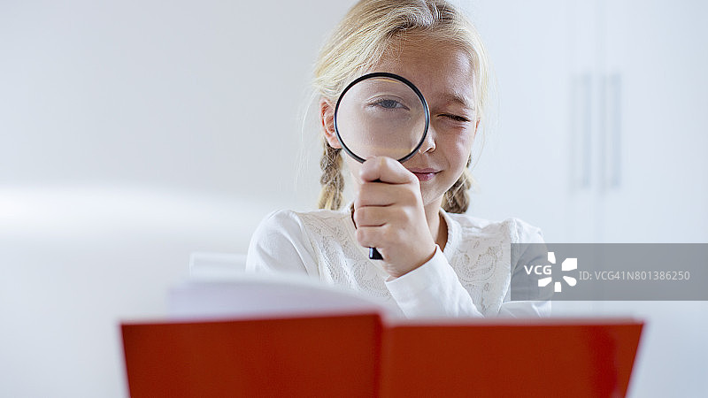 金发小女孩用放大镜观察图片素材