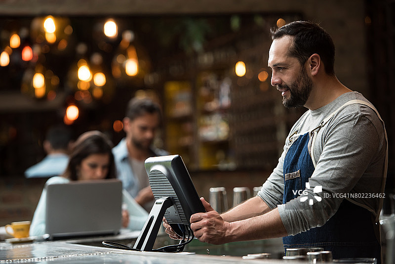 男服务员在餐厅的电脑上下订单图片素材