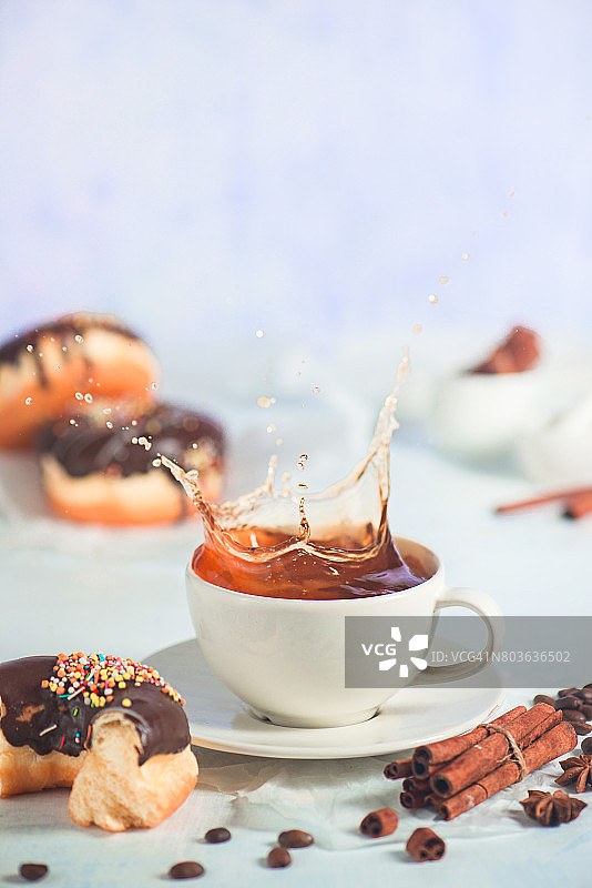 咖啡杯中的咖啡飞溅，配以巧克力甜甜圈图片素材