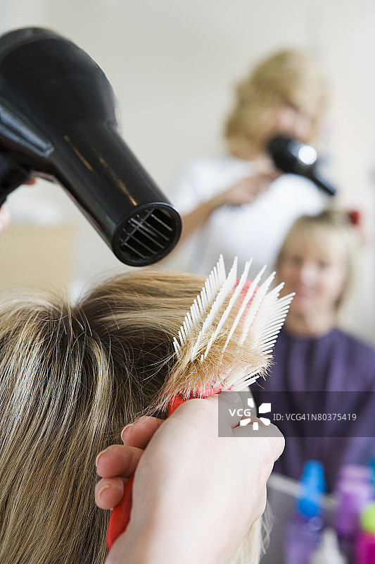 手持吹风机吹头发图片素材