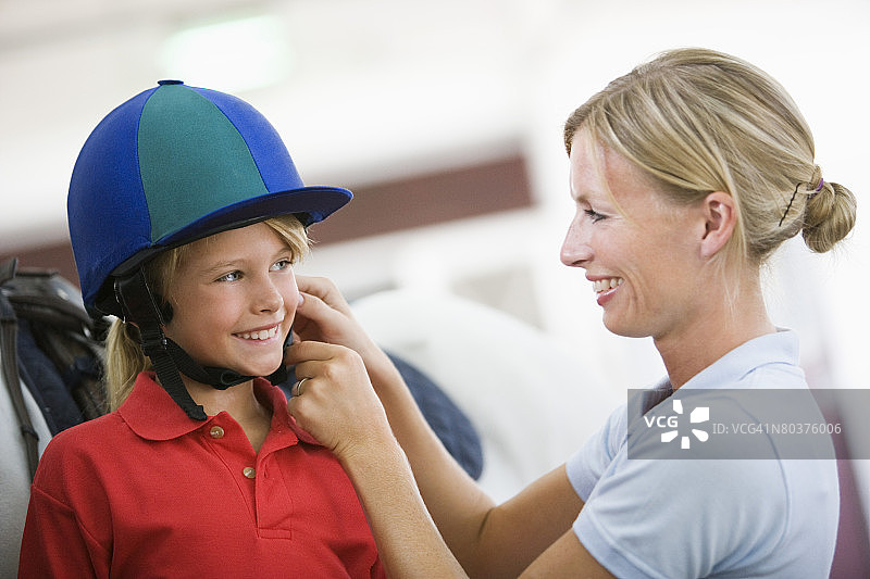 女人为女孩系好骑行头盔图片素材