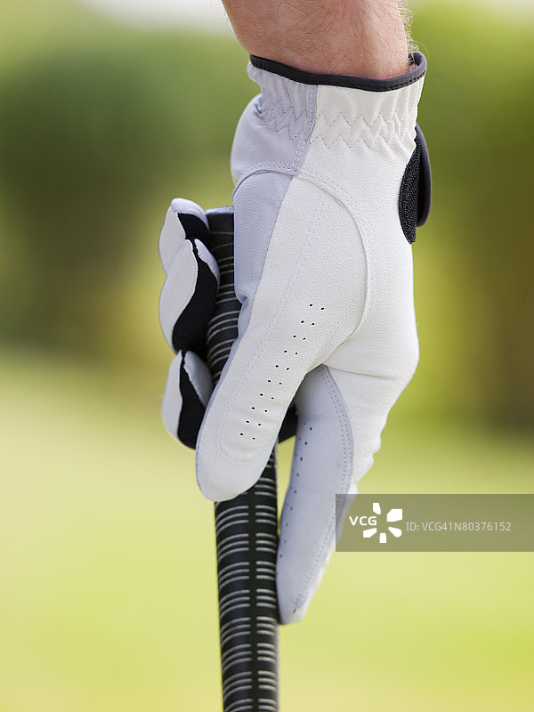 戴手套的手拿着高尔夫球杆图片素材