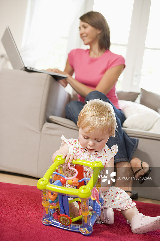 儿童玩玩具，母亲使用笔记本电脑图片素材
