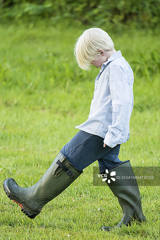 穿着过大橡胶靴的小男孩图片素材