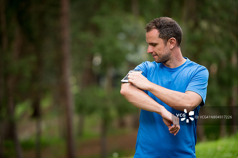 跑步者佩戴臂带使用手机图片素材