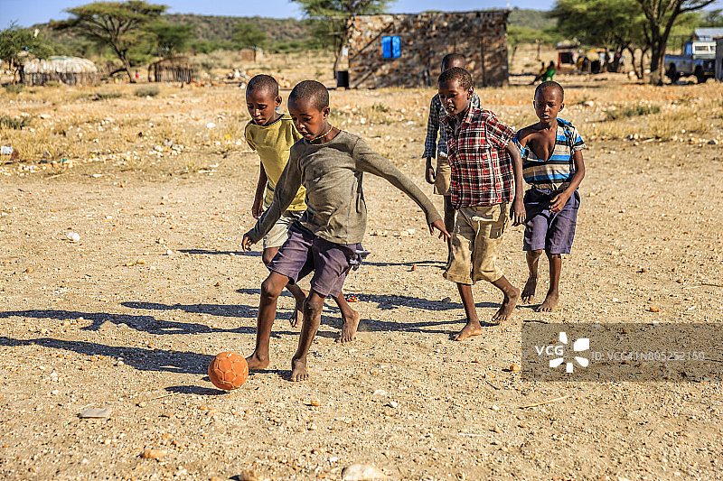 东非村庄里赤脚踢足球的非洲儿童图片素材