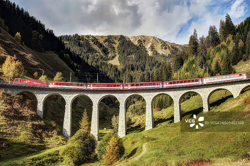 红色列车通过瑞士阿尔卑斯山的高架桥图片素材