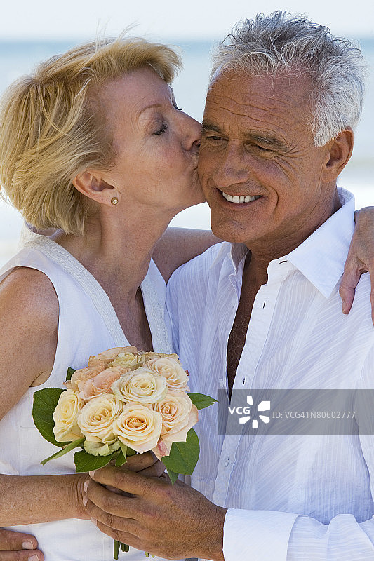 在沙滩上亲吻男人的女人与鲜花图片素材