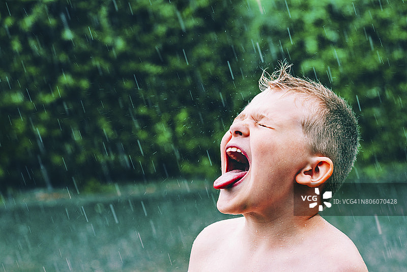 夏雨倾盆，男孩品尝雨滴图片素材