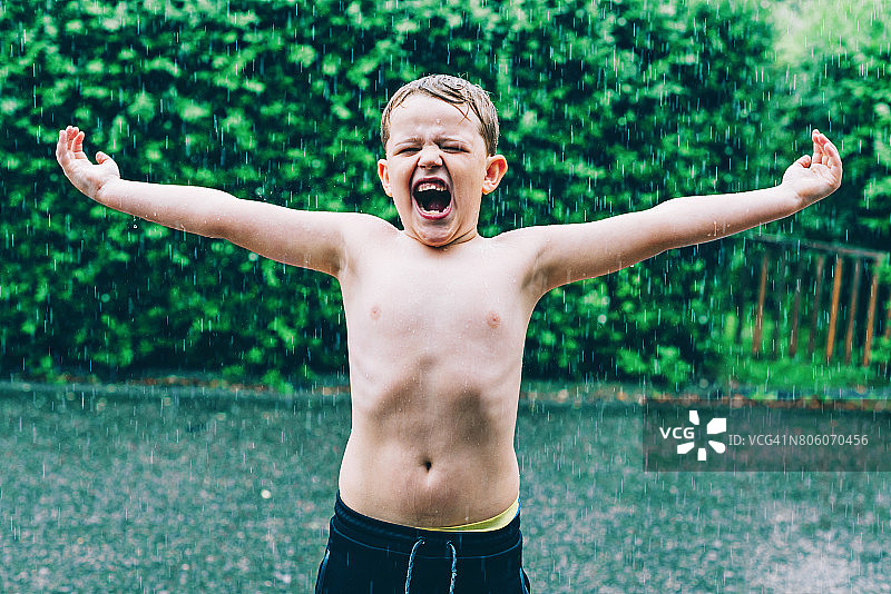 男孩在倾盆大雨中淋雨图片素材