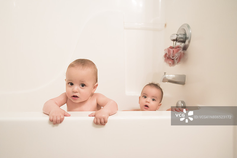 12个月大的双胞胎男孩一起在浴缸里玩耍图片素材