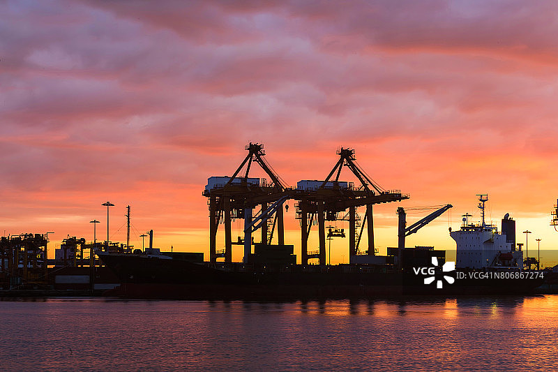 货船在港口装载集装箱日落图片素材