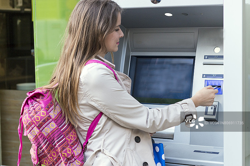 美丽女孩将信用卡插入ATM机图片素材
