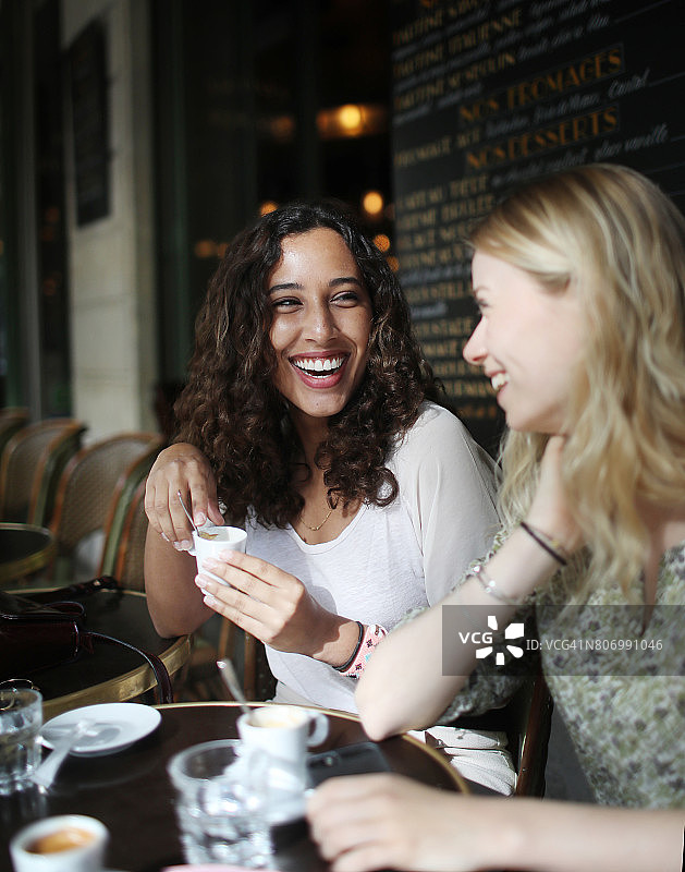 在巴黎咖啡馆露台上交谈的两位年轻女子图片素材