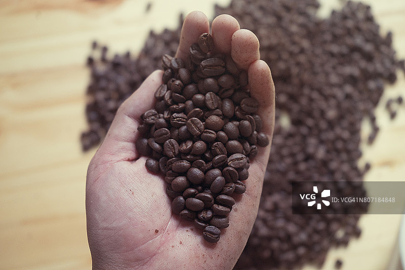 咖啡师手持烘焙的非洲咖啡豆和浓缩咖啡杯图片素材