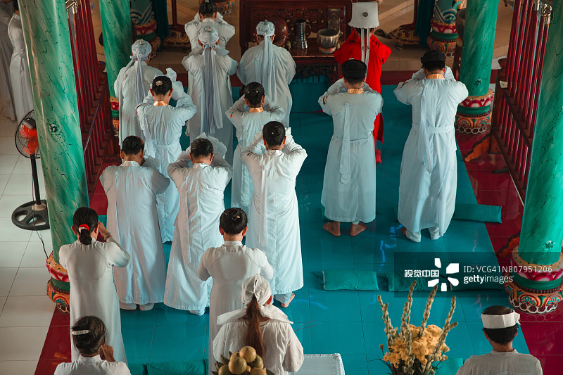在越南湄公河三角洲高台寺穿着传统长袍的宗教信徒祈祷图片素材