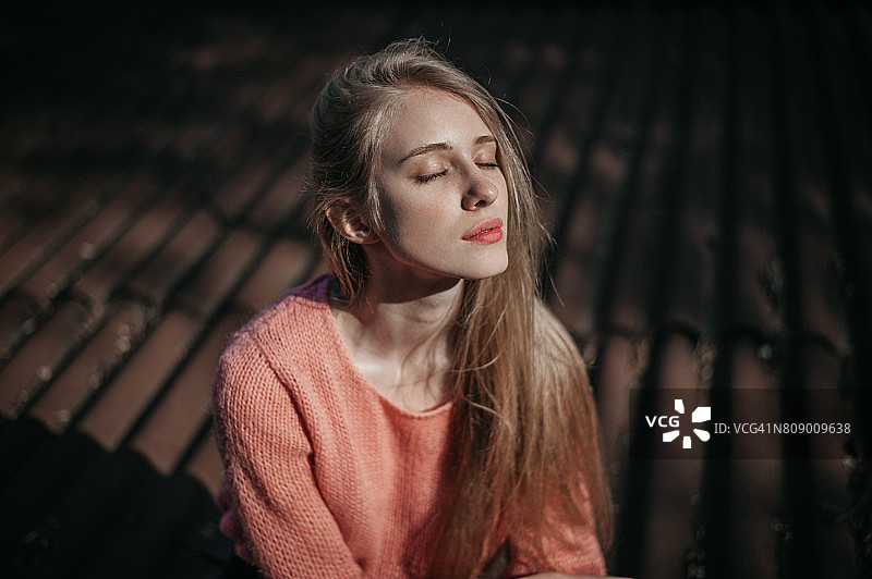 日出时，女人坐在屋顶上图片素材