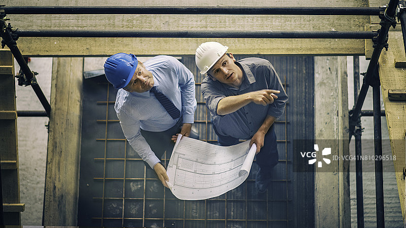 两位建筑师在建筑工地上查看蓝图图片素材
