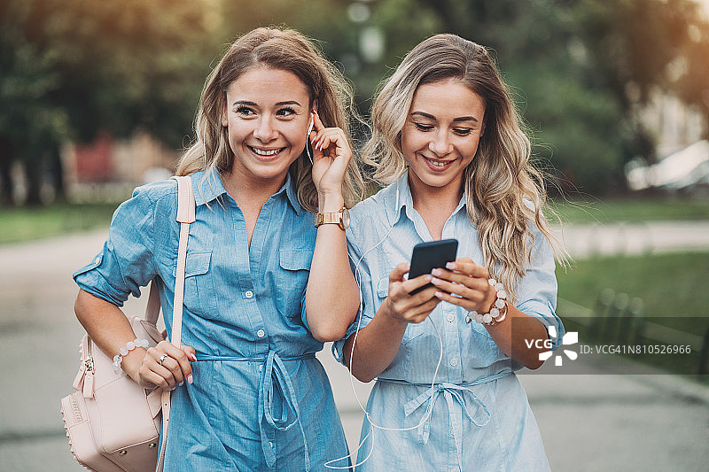 用智能手机和耳机的美丽姐妹图片素材