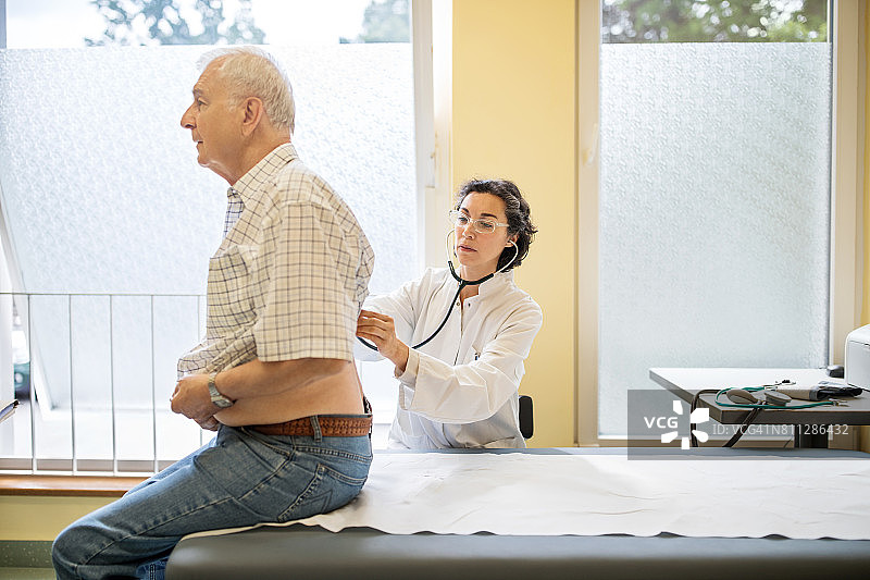 医生在诊室检查老年男性的呼吸图片素材