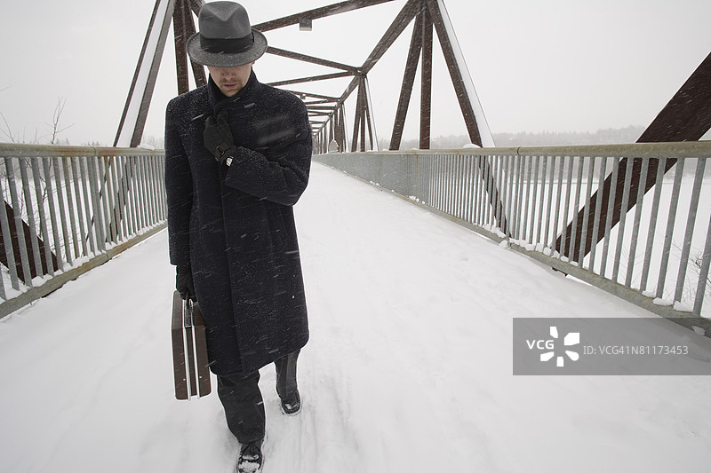 商人走过一座被雪覆盖的桥图片素材