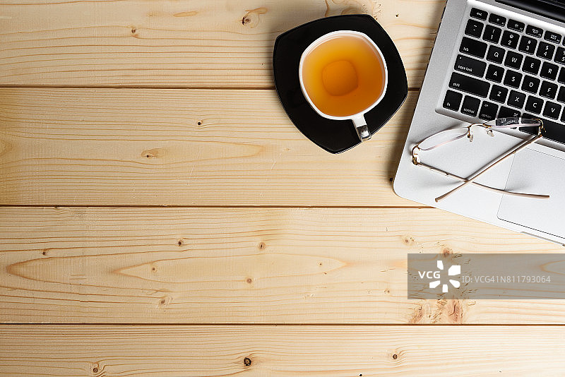 办公桌桌面俯视图，配有绿茶杯、电脑键盘和眼镜图片素材