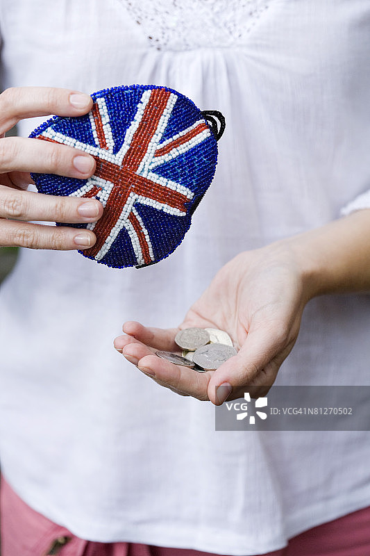 拿着英国国旗硬币钱包里的硬币的女人图片素材