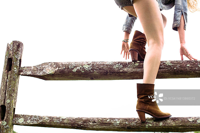 年轻女人爬木栅栏图片素材