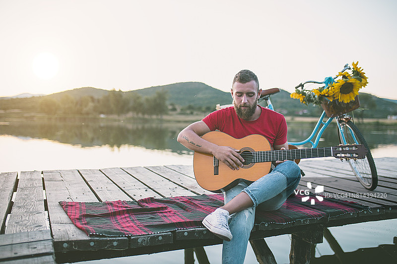 在湖边弹吉他的时髦男人图片素材