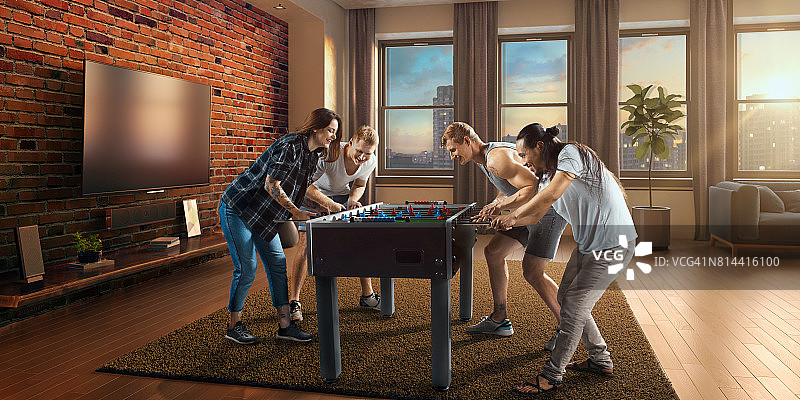 朋友们兴致勃勃地玩桌上足球游戏图片素材