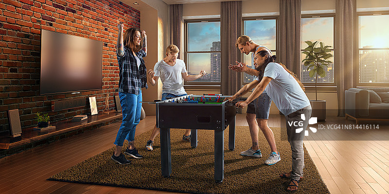 朋友们玩桌上足球游戏，一队人兴奋地庆祝胜利图片素材