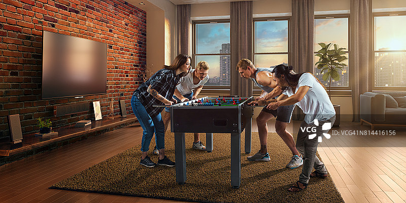 朋友们兴致勃勃地玩桌上足球游戏图片素材