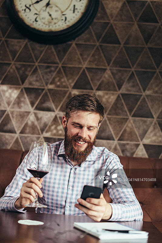 商人喝红酒并用手机发短信图片素材
