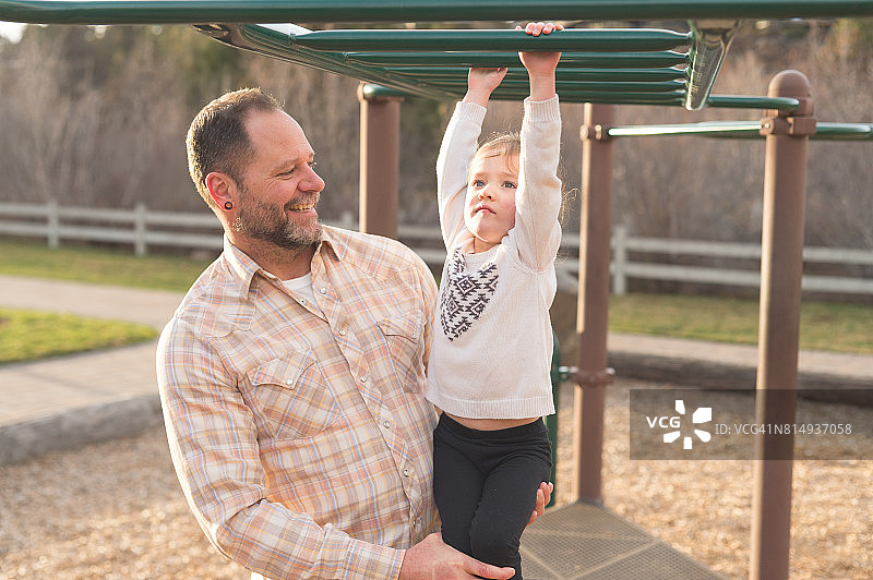 爸爸帮小女儿在游乐场学攀爬架图片素材