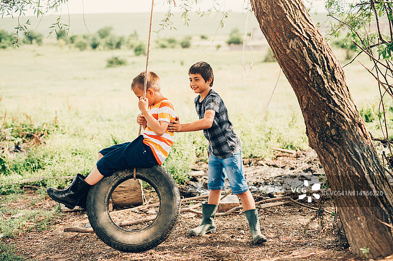 小男孩在轮胎上荡秋千图片素材