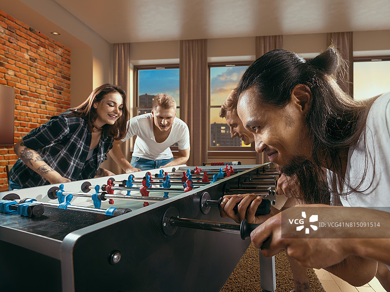 朋友们兴致勃勃地玩桌上足球游戏图片素材