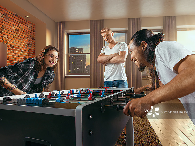 朋友们兴致勃勃地玩桌上足球游戏图片素材