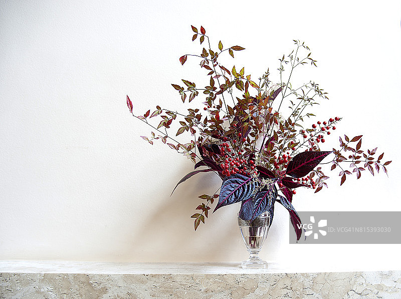 壁炉架上摆放着一瓶带有秋季植物和花卉的插花图片素材