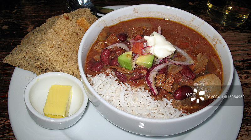 牛肉辣椒配芸豆、米饭、酸奶油、牛油果、番茄、红洋葱和新鲜面包图片素材