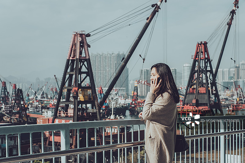 在繁忙的集装箱码头，女商人在城市里打电话图片素材