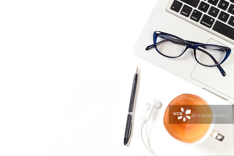 俯视：白色办公桌，配有笔记本电脑、茶、眼镜、笔和耳机图片素材