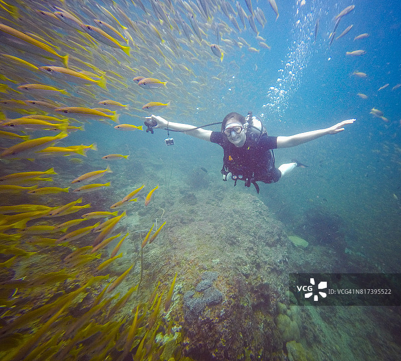 快乐的女潜水员与大眼鲷鱼群图片素材