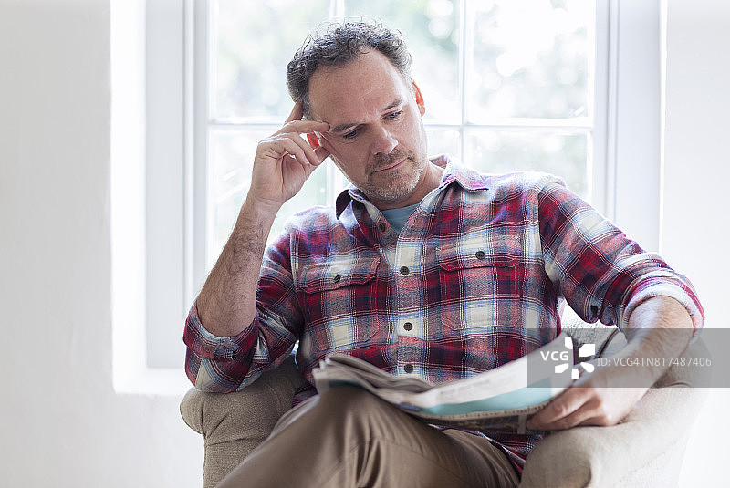在扶手椅上阅读报纸的男人图片素材