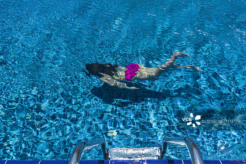 在游泳池里水下游泳的年轻女人图片素材
