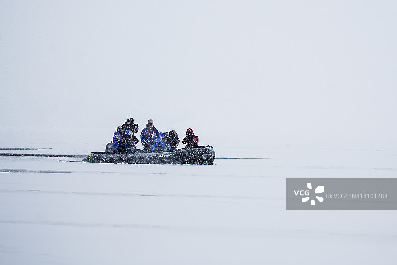 北极雪暴中挤满游客的充气船图片素材
