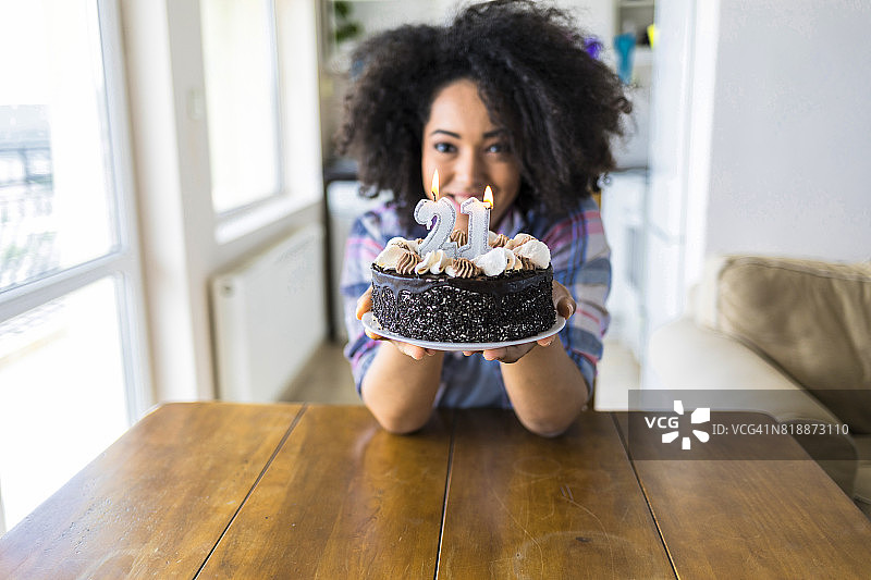 手捧生日蜡烛蛋糕的非洲裔女人图片素材